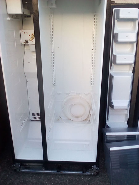 tuyau enroulé en bas du frigo noir